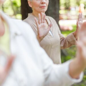 Mujer practicando Chikung en un parque para aliviar los sofocos de la menopausia